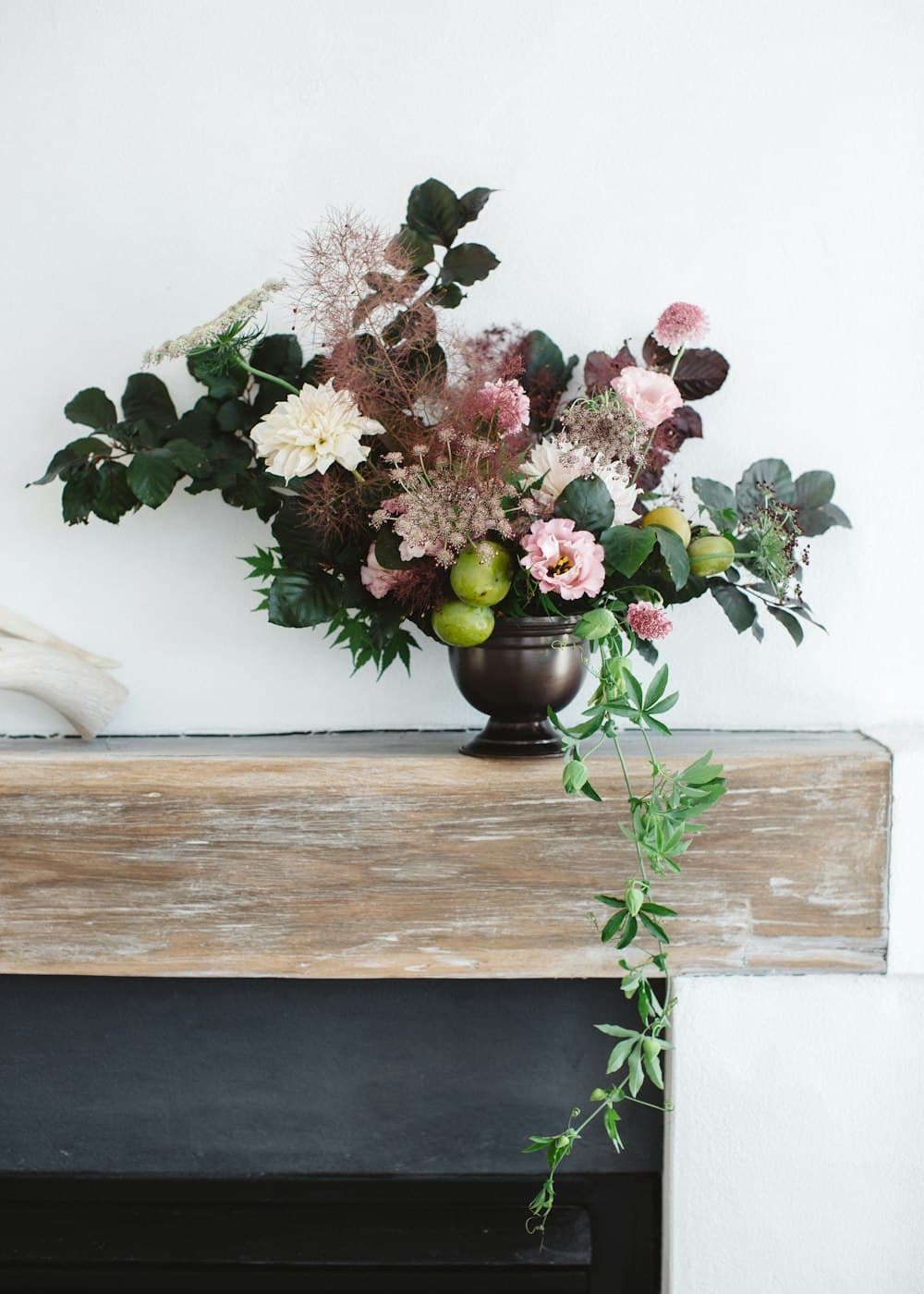 Blumenarrangement in einer Vase auf einem Holzsims